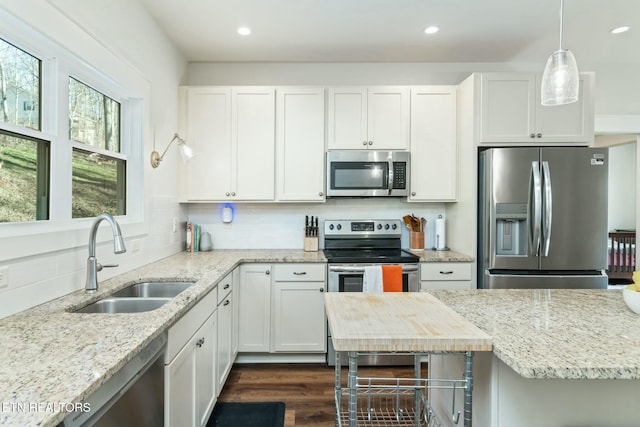 kitchen with stainless steel appliances, white cabinetry, sink, and pendant lighting