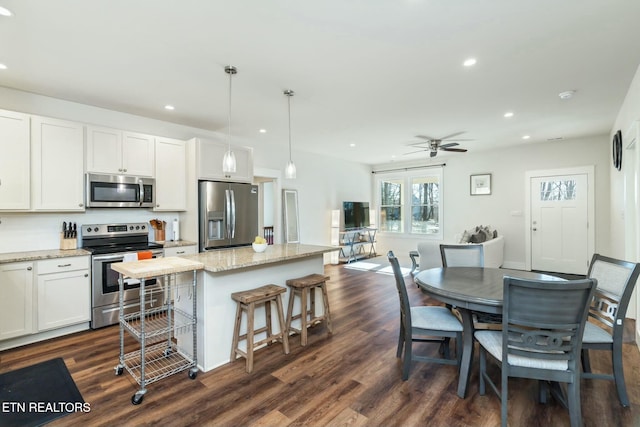 kitchen featuring stainless steel appliances, white cabinetry, a center island, ceiling fan, and pendant lighting