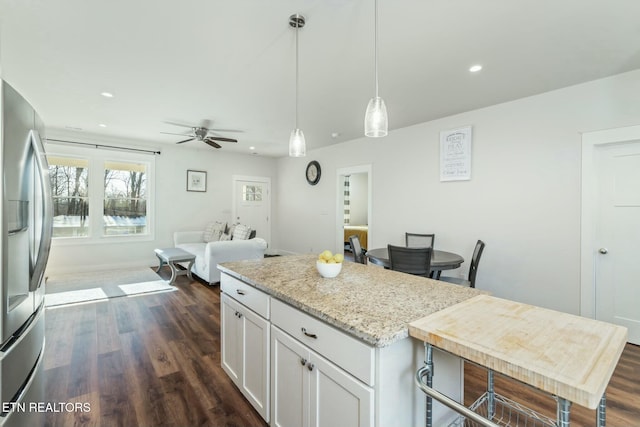 kitchen featuring stainless steel fridge with ice dispenser, light stone countertops, ceiling fan, white cabinets, and decorative light fixtures