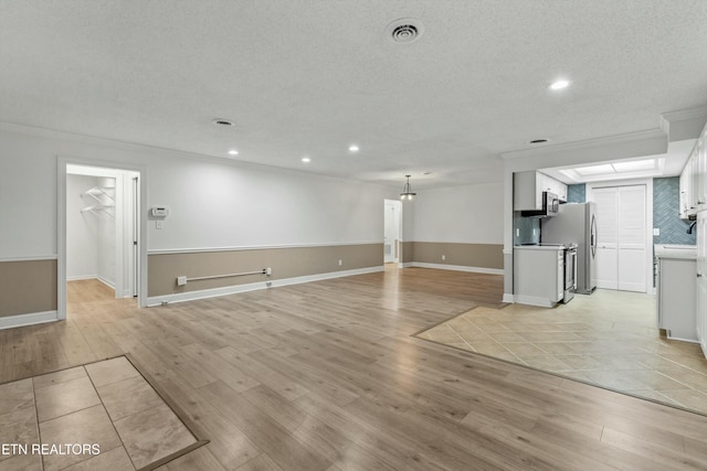 unfurnished living room featuring light wood-type flooring, ornamental molding, and a textured ceiling