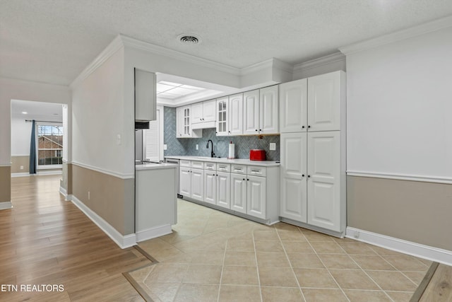 kitchen with ornamental molding, a textured ceiling, sink, white cabinets, and tasteful backsplash