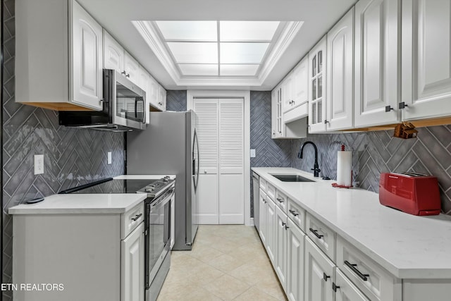 kitchen with sink, stainless steel appliances, white cabinets, tasteful backsplash, and light tile patterned floors