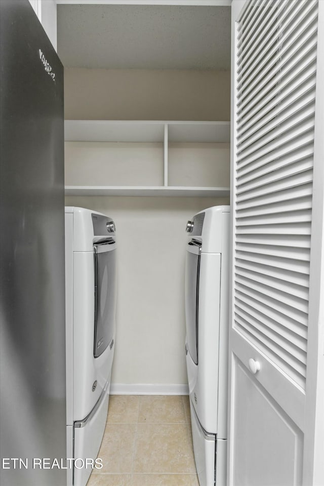 clothes washing area featuring washer and dryer and light tile patterned floors