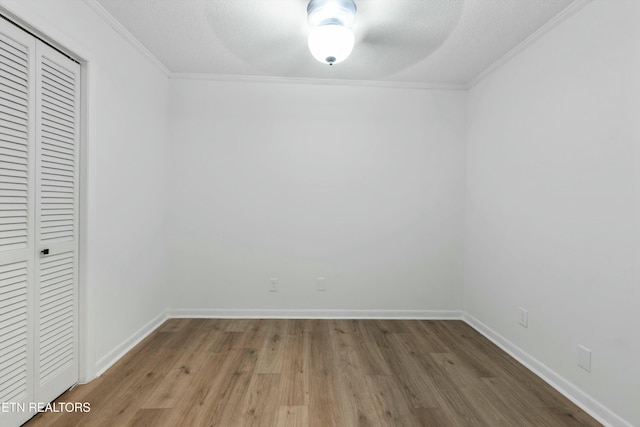 interior space with a textured ceiling, crown molding, and wood-type flooring