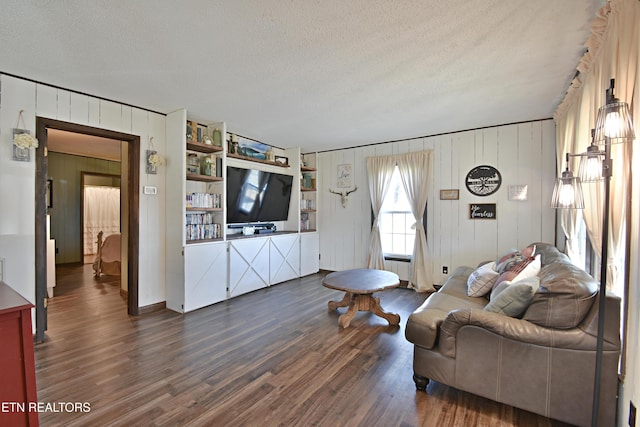 living room featuring dark hardwood / wood-style flooring, wood walls, and a textured ceiling