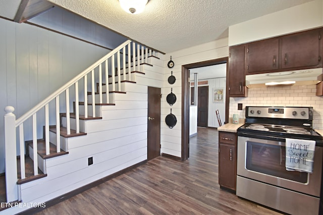 kitchen featuring a textured ceiling, dark hardwood / wood-style flooring, wood walls, stainless steel range with electric stovetop, and dark brown cabinets