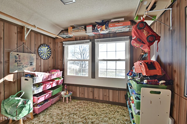 interior space featuring wood walls, a textured ceiling, and lofted ceiling