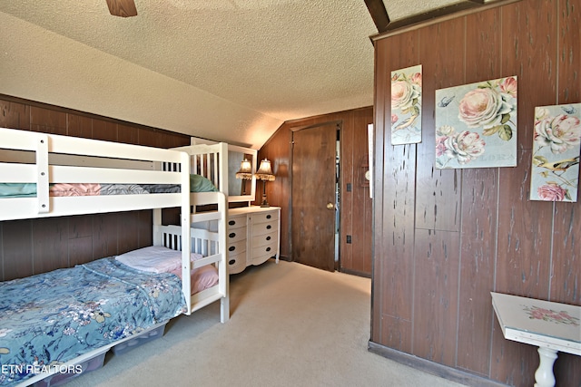 bedroom featuring vaulted ceiling, ceiling fan, light colored carpet, and wooden walls