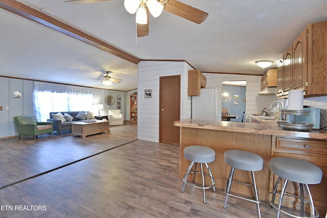 kitchen featuring white refrigerator, sink, dark hardwood / wood-style floors, wood walls, and lofted ceiling with beams