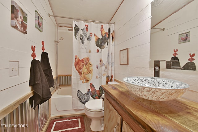 full bathroom featuring toilet, vanity, wood walls, and shower / bath combination with curtain