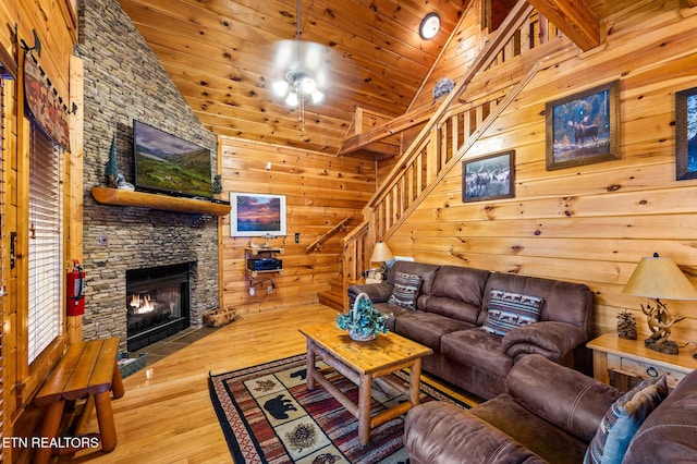 living room featuring hardwood / wood-style floors, beam ceiling, wood ceiling, and a stone fireplace