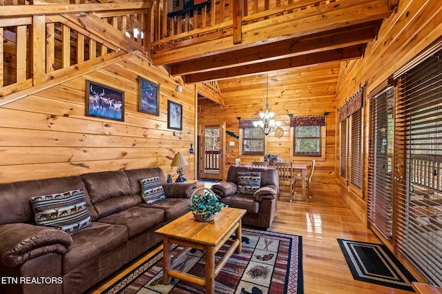 living room featuring beam ceiling, light hardwood / wood-style floors, wood walls, and a chandelier