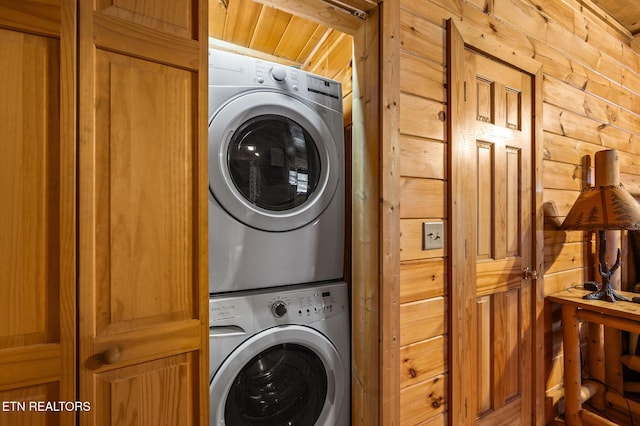 washroom with wood walls and stacked washer and clothes dryer