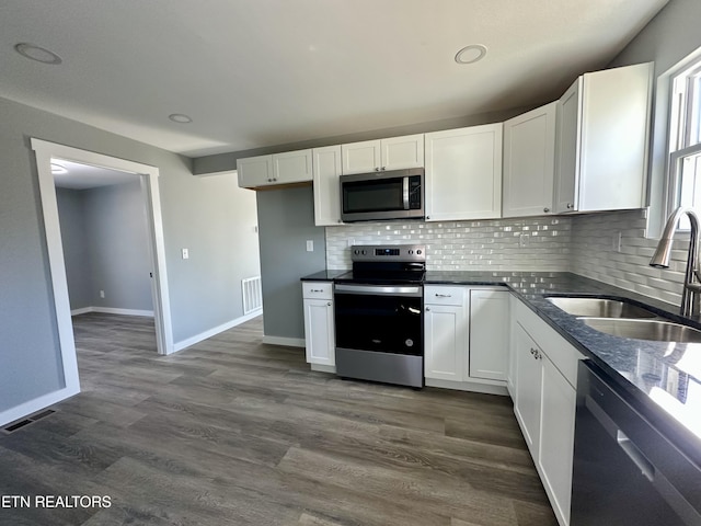 kitchen featuring stainless steel appliances, sink, white cabinets, decorative backsplash, and dark hardwood / wood-style floors