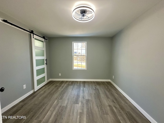 spare room with a barn door and dark hardwood / wood-style flooring