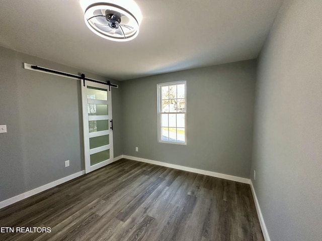 spare room with dark hardwood / wood-style flooring and a barn door