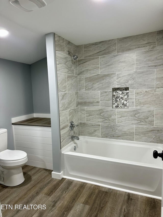 bathroom with toilet, wood-type flooring, and tiled shower / bath combo