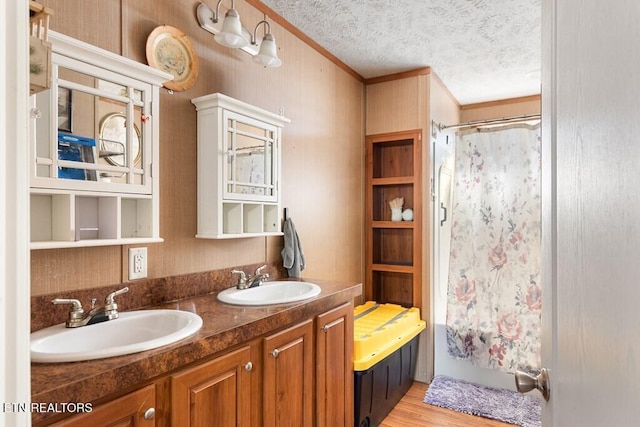 bathroom featuring wood-type flooring, walk in shower, a textured ceiling, crown molding, and vanity