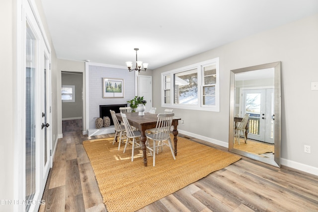 dining room with a brick fireplace, hardwood / wood-style floors, and a notable chandelier