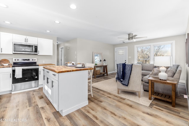 kitchen with white cabinetry, light hardwood / wood-style flooring, wooden counters, and appliances with stainless steel finishes