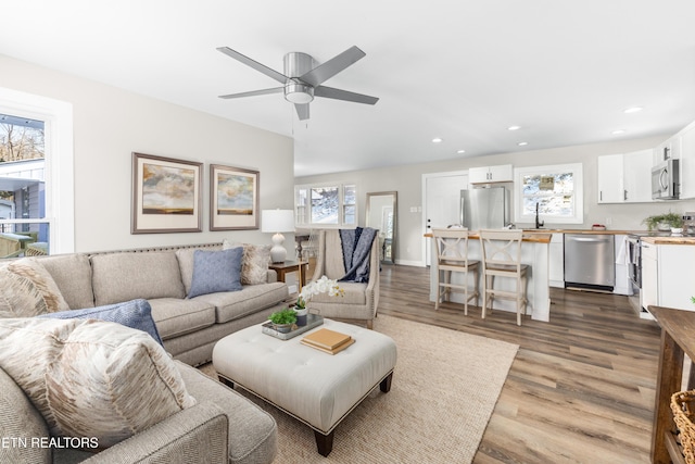 living room featuring sink, wood-type flooring, and ceiling fan