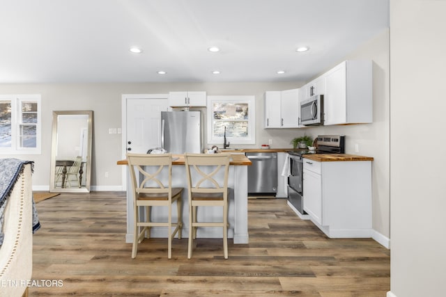 kitchen featuring appliances with stainless steel finishes, a wealth of natural light, butcher block countertops, and white cabinets