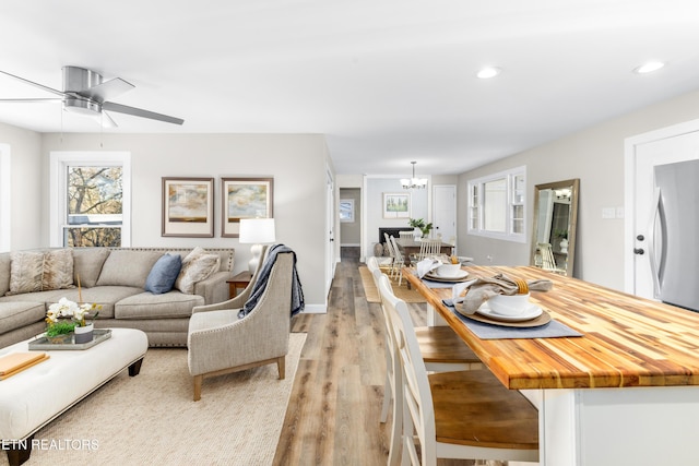 living room featuring ceiling fan with notable chandelier and light hardwood / wood-style floors