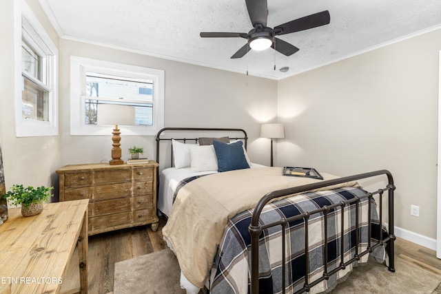 bedroom featuring ceiling fan, ornamental molding, wood-type flooring, and a textured ceiling