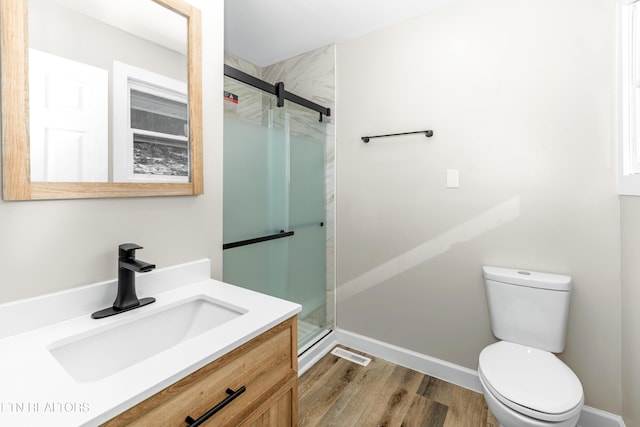 bathroom featuring walk in shower, vanity, toilet, and hardwood / wood-style floors