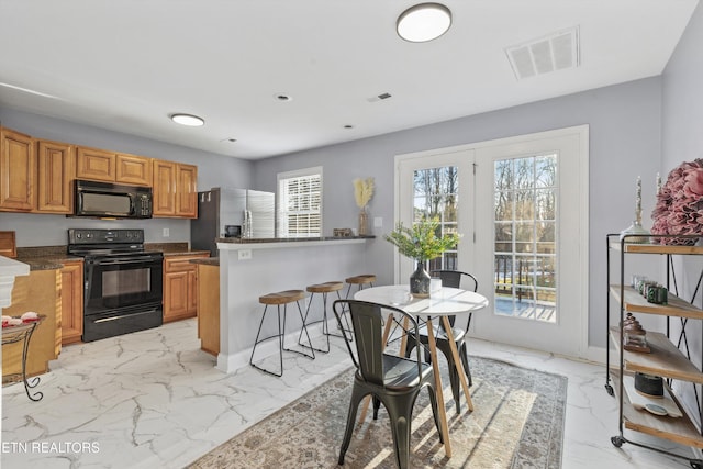 kitchen featuring black appliances, kitchen peninsula, and a kitchen breakfast bar