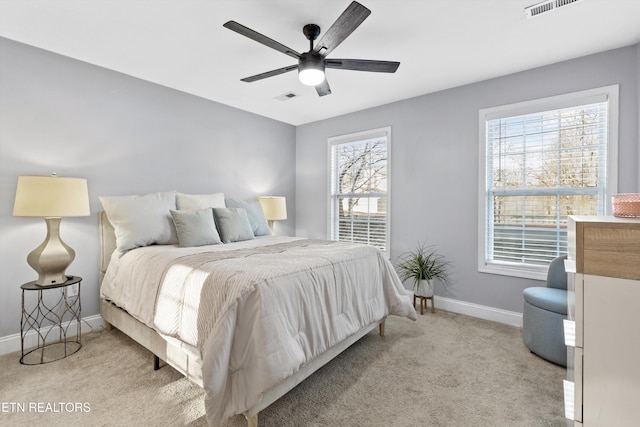 bedroom with ceiling fan, light colored carpet, and multiple windows