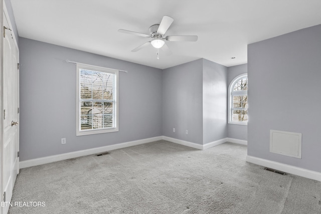 spare room with ceiling fan, light colored carpet, and plenty of natural light