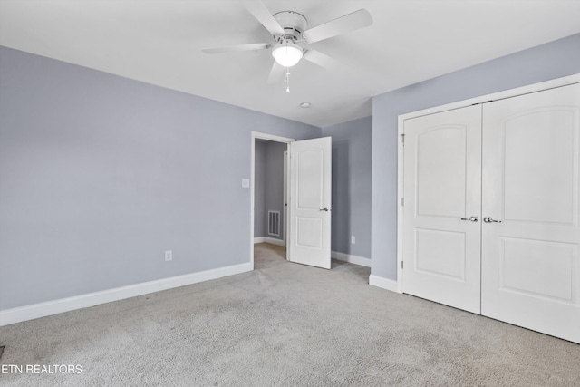 unfurnished bedroom featuring ceiling fan, a closet, and light carpet