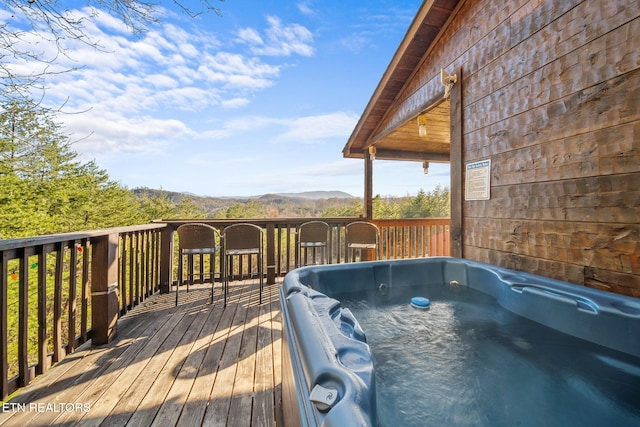 wooden deck with a mountain view and an outdoor hot tub