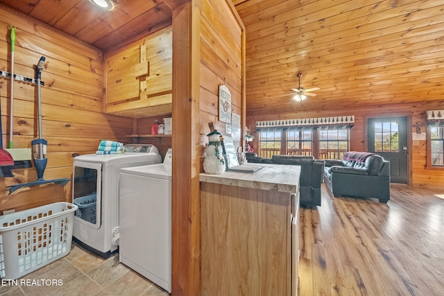 laundry room featuring a high ceiling, wooden walls, cabinets, washing machine and clothes dryer, and ceiling fan