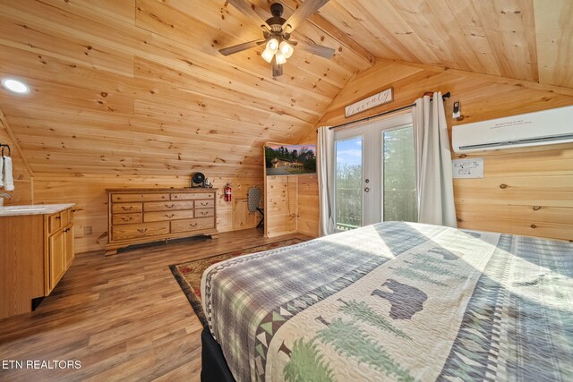 bedroom with a wall mounted air conditioner, light wood-type flooring, access to outside, and wooden walls