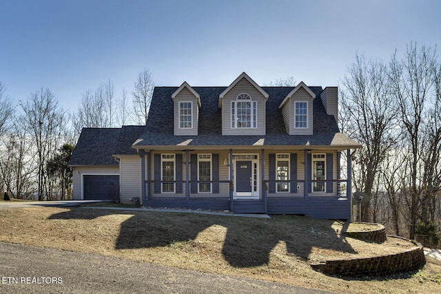 cape cod home featuring a garage and covered porch