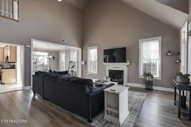 living room featuring plenty of natural light, dark hardwood / wood-style floors, a notable chandelier, and a towering ceiling