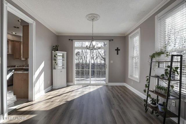 dining area with hardwood / wood-style flooring, ornamental molding, an inviting chandelier, and a textured ceiling