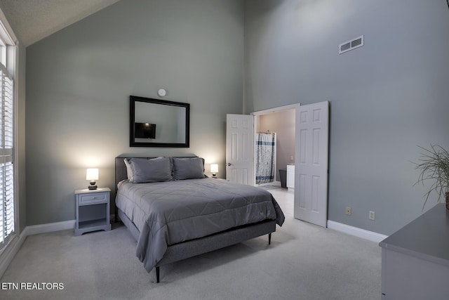 carpeted bedroom with ensuite bath and high vaulted ceiling