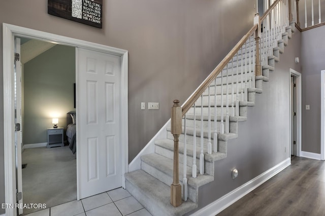 stairs featuring a towering ceiling and tile patterned floors