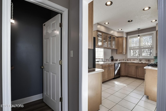 kitchen featuring pendant lighting, sink, light tile patterned floors, a textured ceiling, and stainless steel dishwasher