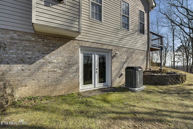 rear view of property with central AC unit, a yard, and french doors