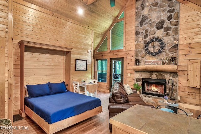 bedroom featuring hardwood / wood-style floors, wood walls, and high vaulted ceiling