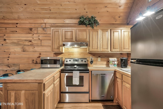 kitchen with lofted ceiling, light brown cabinetry, wooden walls, and stainless steel appliances