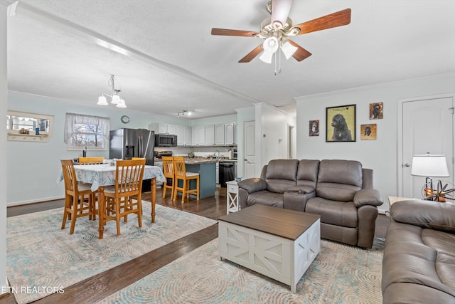 living room featuring ornamental molding, ceiling fan with notable chandelier, a textured ceiling, and hardwood / wood-style flooring