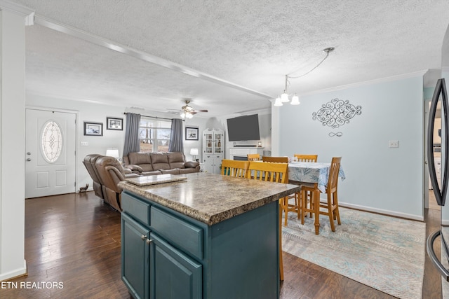 kitchen with a center island, crown molding, a textured ceiling, dark hardwood / wood-style flooring, and ceiling fan with notable chandelier