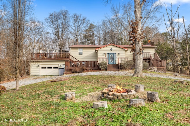 view of front facade featuring an outdoor fire pit, a front yard, and a wooden deck