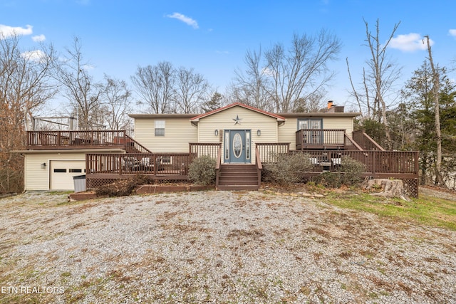 rear view of property featuring a garage and a wooden deck