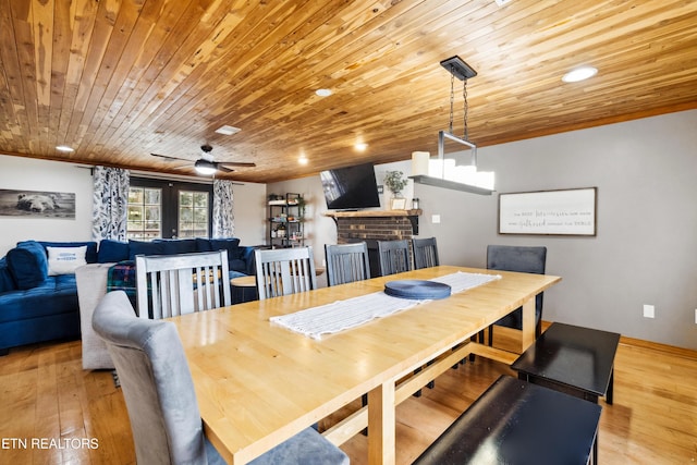 dining space featuring wooden ceiling, a fireplace, french doors, light wood-type flooring, and ceiling fan